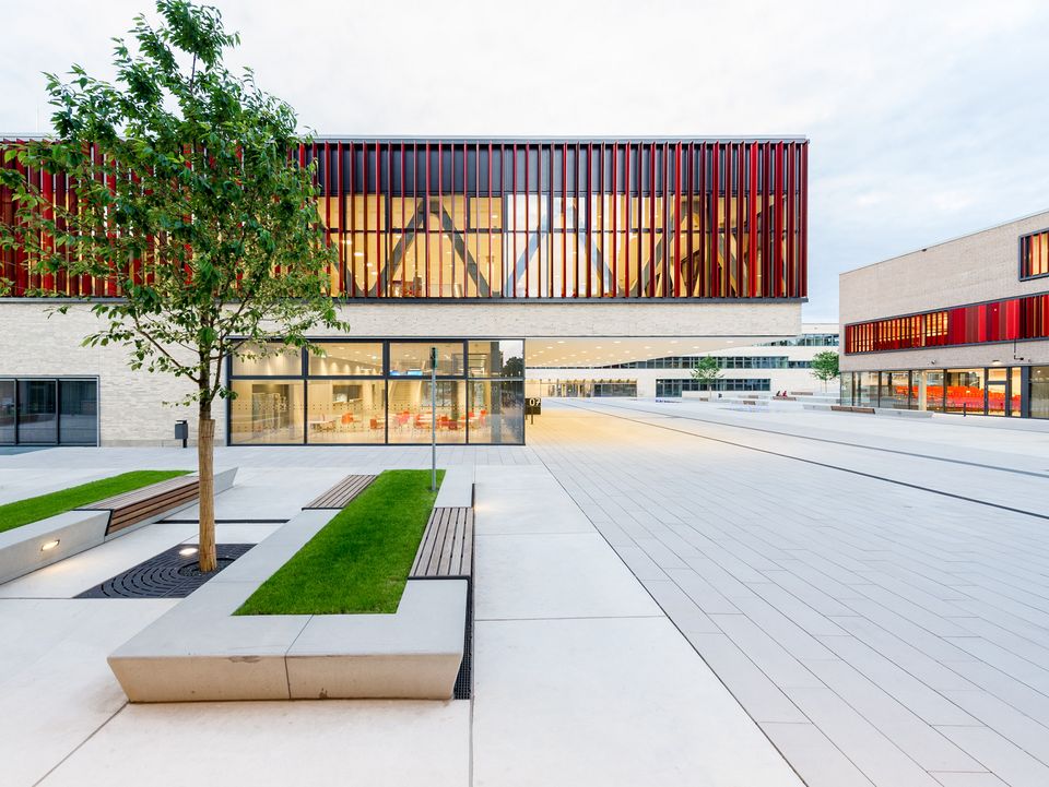 Exterior view of a university campus featuring glazed buildings, structured pedestrian routes and open square areas.