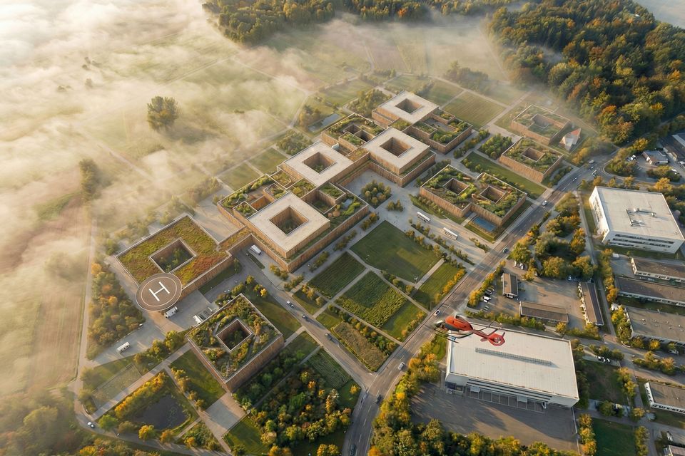 Aerial view of a hospital campus featuring landscaped courtyards, modular building arrangements, helicopter‑capable areas and extensive open spaces.