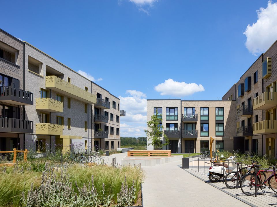 Exterior view of a central courtyard with pathways, seating areas and surrounding residential buildings.