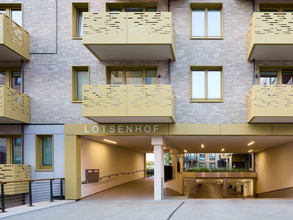 Exterior view of a residential building with patterned balconies and a covered passage leading to the Lotsenhof courtyard.
