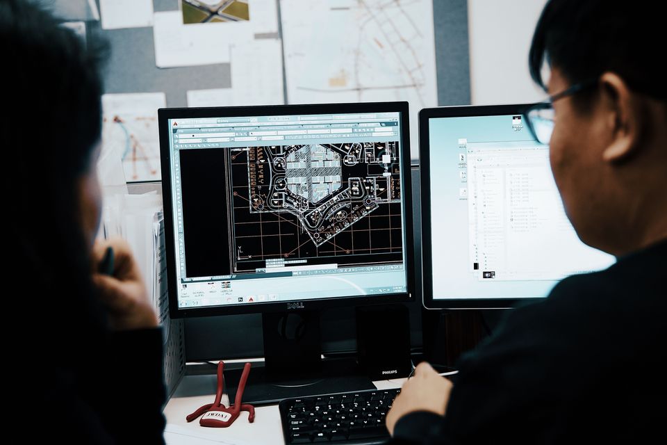 Interior view of an architecture office with a project group seated around a table, architectural models, plans and work materials in an open meeting zone.