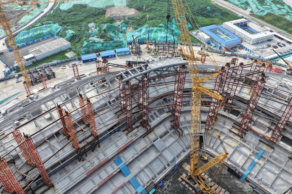 Detailed view of the arena construction showing steel beams, rows of columns and crane equipment.