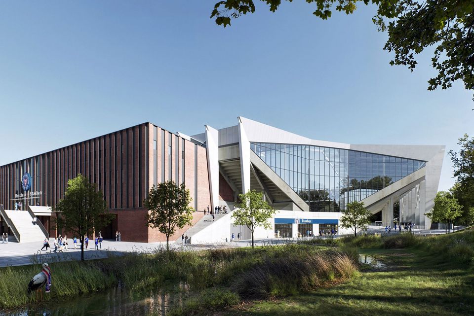 Exterior view of the stadium from the landscaped surroundings, showing entrance areas, the distinctive façade structure and green outdoor spaces.