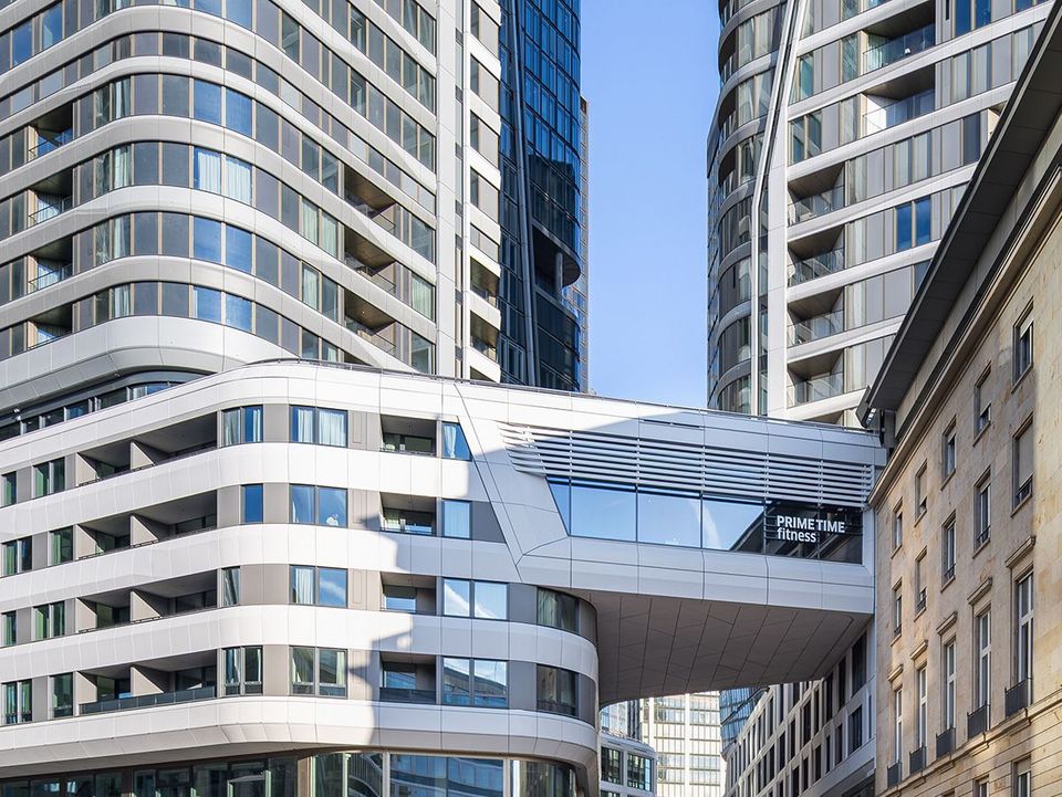 Außenaufnahme eines Hochhauses mit markanter Fassade, vertikalen Designlinien und umliegender urbaner Bebauung im Stadtkontext.