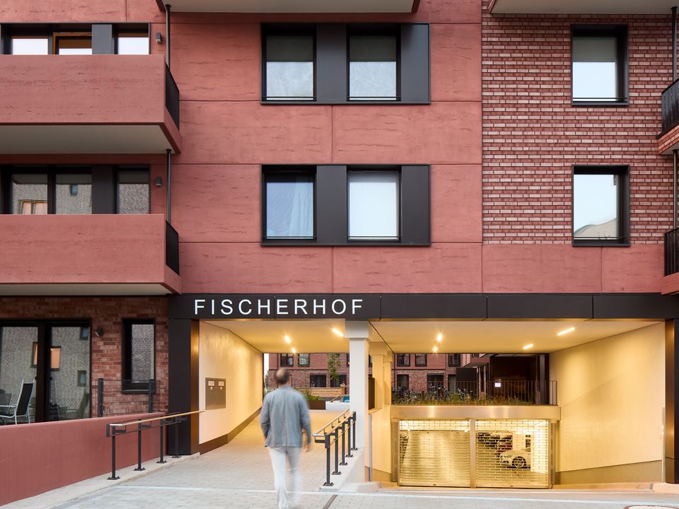 Exterior view of the Fischerhof residential building with a covered passage leading to the courtyard.